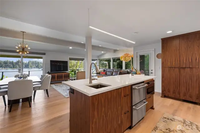Kitchen cabinets are grain matched walnut with quartz counters.  Island features a prep sink, drawer microwave & drawer refrigerator.  Door to the left of the pantry cabinet accesses the deck for dining & grill access.