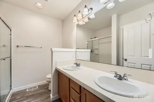 The primary bathroom features a double vanity and large linen closet next to the standing shower.