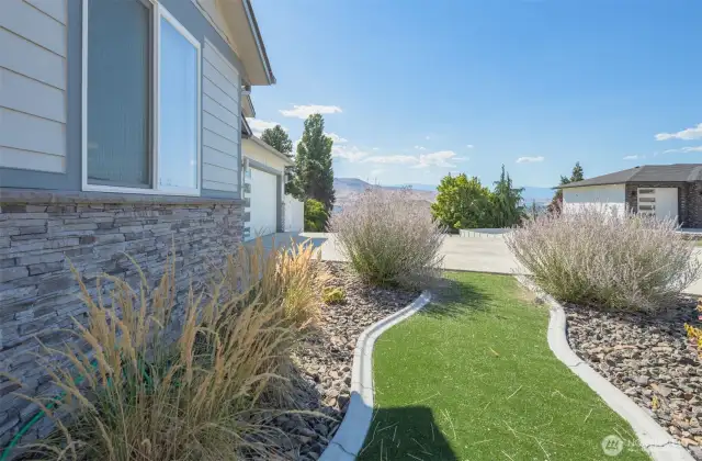 Landscaped front yard featuring decorative rock and lush turf for low-maintenance living and enhanced curb appeal.