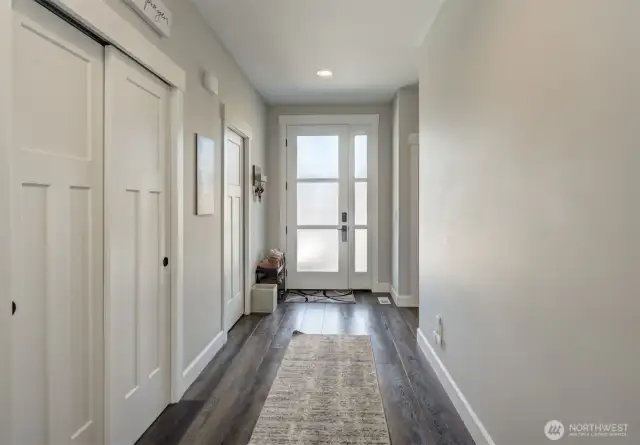 Down the hall, two additional bedrooms are located to the right, separate from the primary suite, while the laundry room and garage are conveniently to the left.