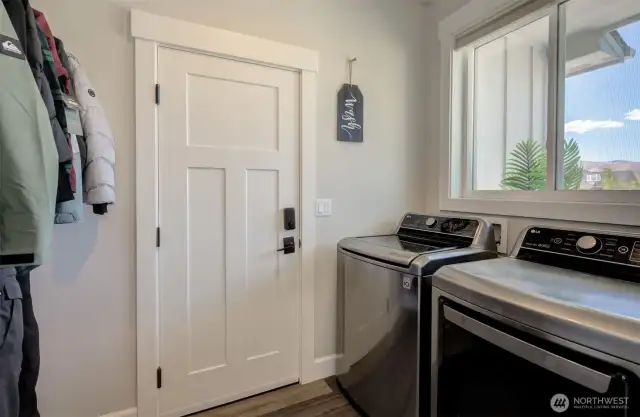 The utility room, located across the hall, leads to the garage and includes built-in cabinetry and a clothing rack for easy organization.