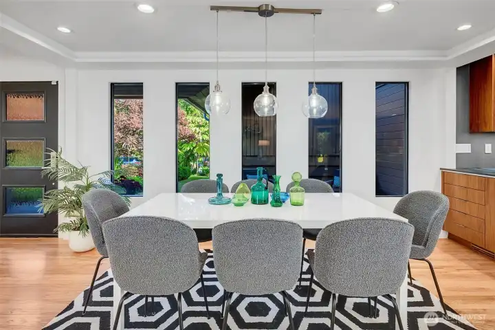Beautiful custom windows look out at the extensive garden foliage and covered sitting area in the front of the home. The cabinets facing the dining area serve as a buffet for silverware, linens, and extra storage needs.