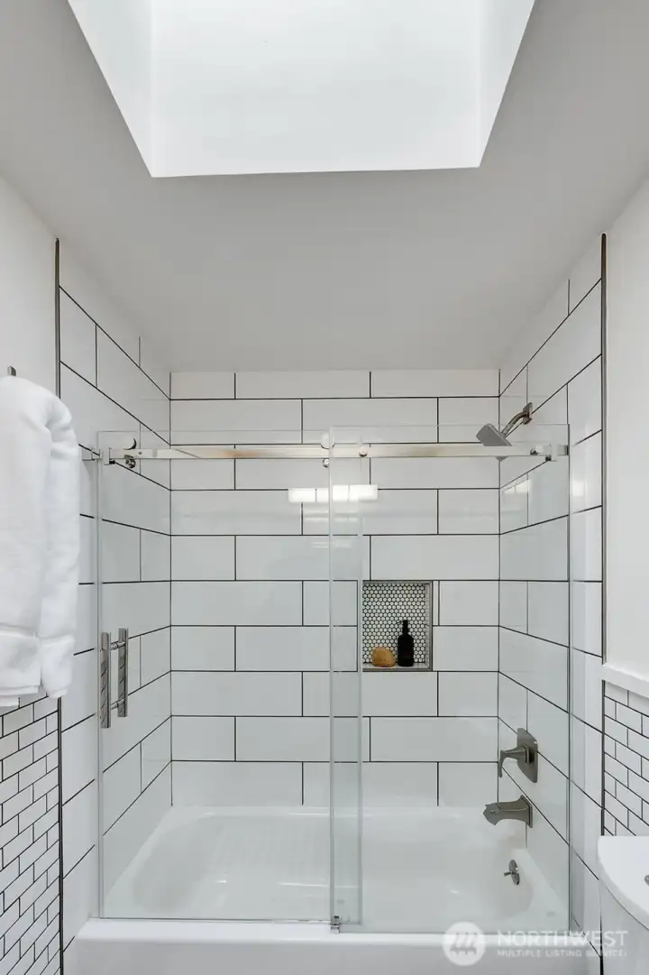 The main guest bath serves the two bedrooms on the east side of the home. Recently updated with crisp subway tile and custom glass shower doors. The skylight provides extra light.