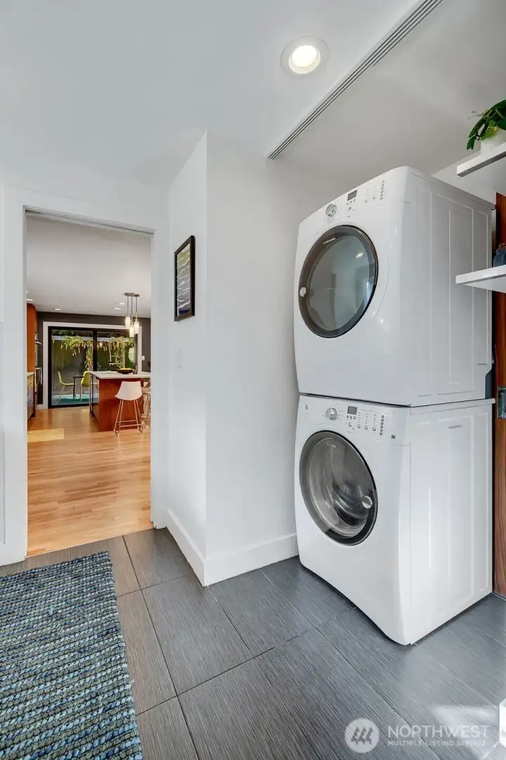 The spacious laundry room with a pocket door (which can be used to separate the space) has a utility sink, a built-in storage pantry, and a second dishwasher for all your entertaining needs. To the right of the stackable washer and dryer, there is a brand new tankless water heater behind the custom panel that matches the kitchen cabinetry. Easy access to the two-car garage with extra built-in storage from the home.