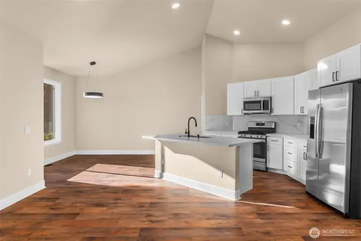 The updated kitchen features brand new cabinets, quartz countertops, new flooring, and GE stainless steel appliances including a refrigerator, gas range, microwave hood, and dishwasher.