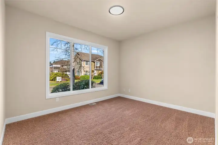 The second bedroom is bright and airy, featuring large windows that flood the space with natural light.