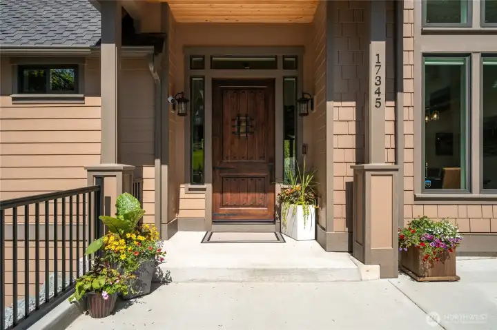 Beautiful front porch with railing to view the front stairs and naturescape planter beds.