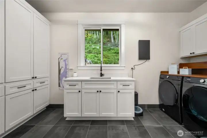 Large mudroom with 4 sets of oversized custom cabinetry to keep items contained, plus a quartz countertop and undermount sink and washer/dryer. Large mudroom with 4 sets of oversized custom cabinetry to keep items contained, plus a quartz countertop and undermount sink and washer/dryer.