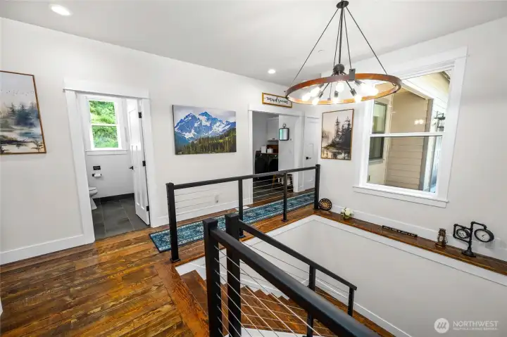 Modern cable railings and chandelier create a contemporay feel with the rustic flooring elements to make this a showstopping feature.