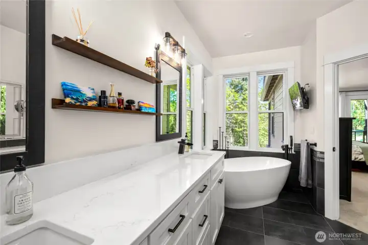 Beautiful primary spa like bath with corner windows to enjoy the nature and matching porcelain tile to the fireplace connects the spaces.