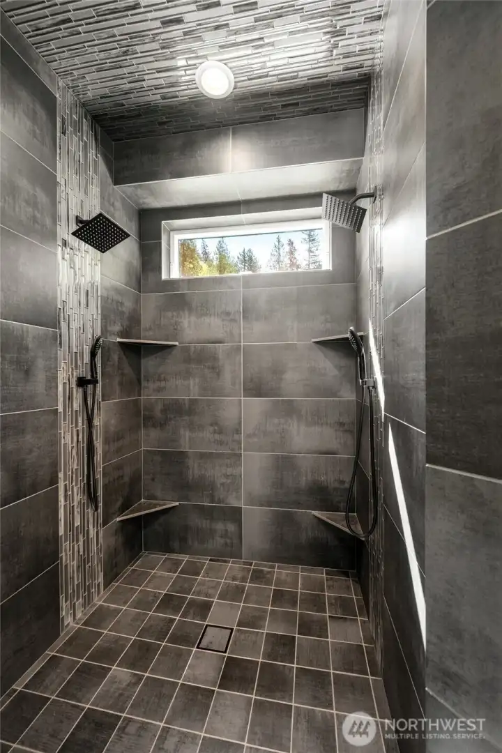 Dual head primary shower with custom cut and polished porcelain tile to match the fireplace to connect the spaces.