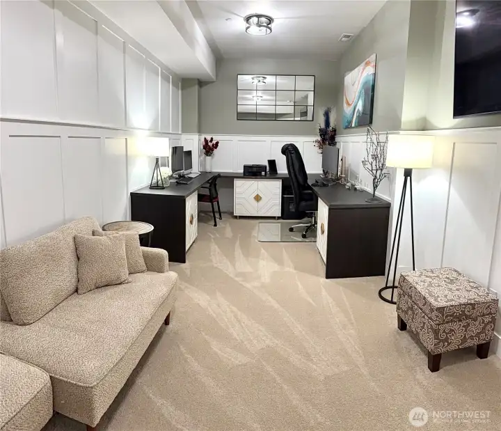 Additional room/office space in basement with floor-to-ceiling wainscoting and built-in U-shaped desk with storage cabinets. Additional room/office space in basement with floor-to-ceiling wainscoting and built-in U-shaped desk with storage cabinets.
