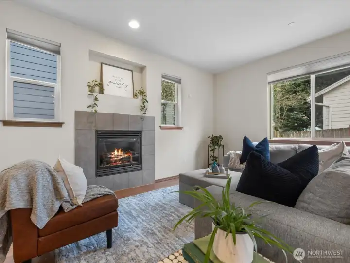 This inviting living room features engineered hardwood flooring and abundant natural light, creating a warm and welcoming atmosphere. The  gas fireplace is complemented by custom built-in shelving—perfect for media or showcasing your favorite décor.