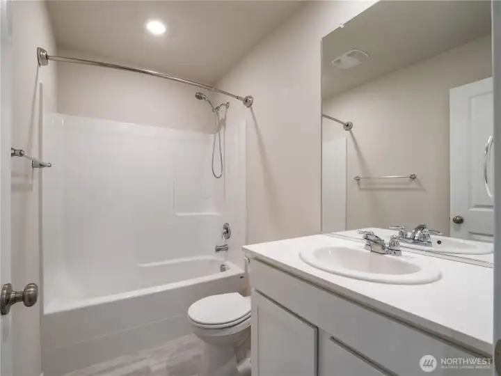 Modern full bathroom with Luxury Vinyl Tile flooring serves the main area of the home.