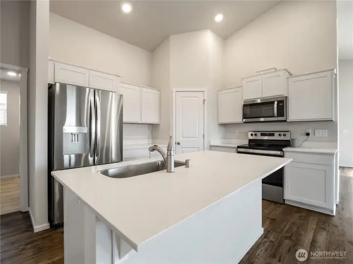 The kitchen is well-lit with ample overhead lighting and natural light from the many nearby windows.