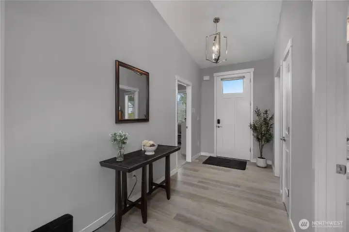 Vaulted entry with upgraded lighting, white trim, and easy access to nearby bedrooms.