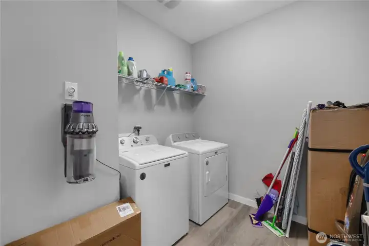 Large utility room with washer and dryer included, storage shelving, and room for household essentials.