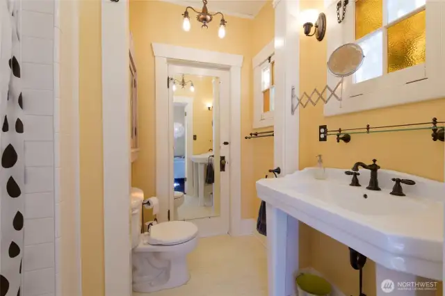 The main floor en suite 3/4 bath enjoys a fully tiled shower and a separate door (with the full-length mirror) to the back porch and courtyard.