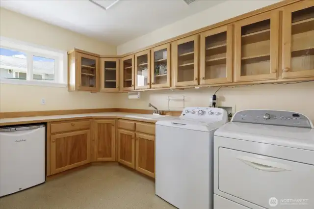 Huge laundry room includes the washer, dryer, & beverage refrigerator & lots of cabinetry for additional storage.
