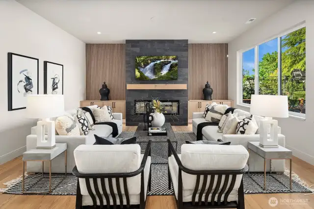 The Great Room on the main level (the front door is to your left after you have walked to the back of the home). This space is designed for both style and functionality, featuring custom-built floating cabinets with beautiful wood detailing on the wall, a striking 60-inch electric fireplace with a beautiful wood mantel. Ceiling-mounted surround sound speakers, this room is primed for the ultimate entertainment experience.