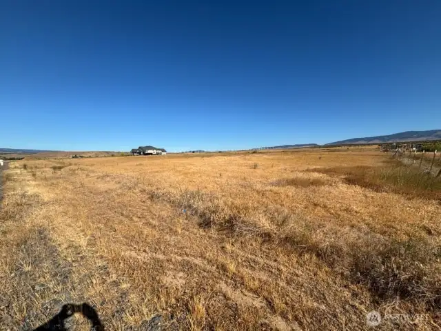 Photo shot from southeast corner of this 5 acre parcel.Almost all the golden dry grass area is the actual lot(not including the neighboring house) .To the right of the home on the horizon are the Valley's white wind mills.