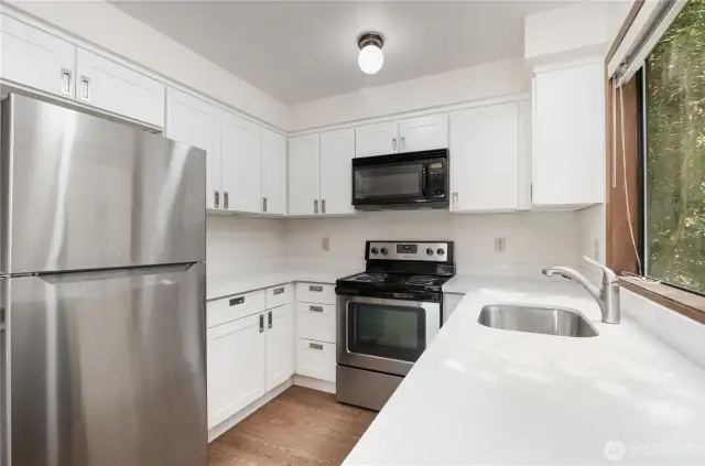 Kitchen features bright cabinetry, stainless steel appliances, and quartz countertops.