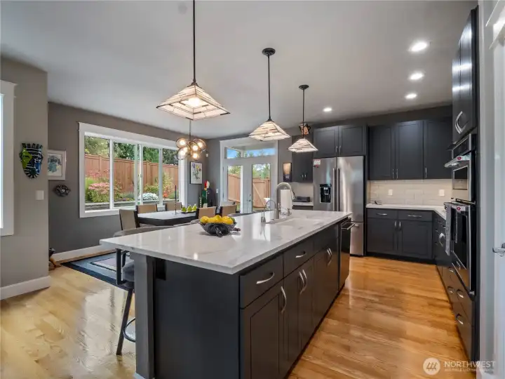 Gleaming quartz countertops and tasteful lighting fixtures in this beautiful kitchen.