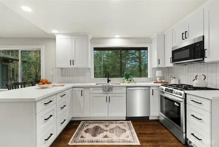 Light-filled and open, this beautifully updated kitchen showcases new backsplash, abundant counter space, a built-in microwave, and a 30-inch five-burner gas range—designed to cook, gather, and entertain with ease.