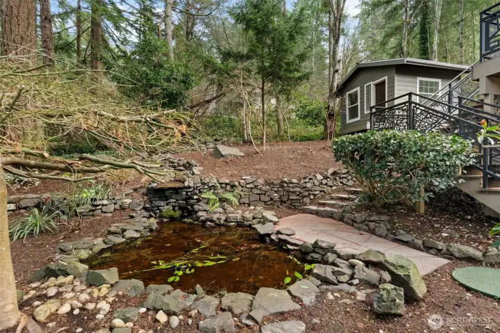 Charming waterfall next to path, close to storage shed usable as office or art room.