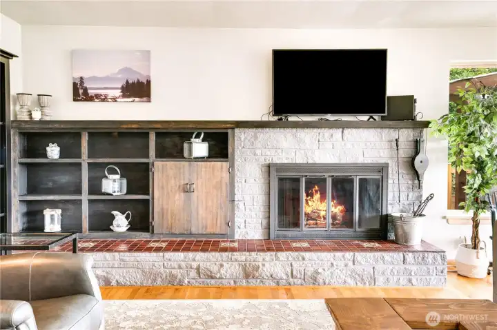 Cozy up beside the wood-burning fireplace, complete with a classic tile hearth and handy firewood passthrough. Built-in living room shelving adds both style and function—perfect for showcasing favorite reads and personal treasures.