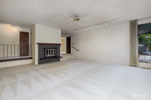 9’ tall ceilings / Ceiling fan  Gas fireplace with brick surround, cement slab heart and wood mantle