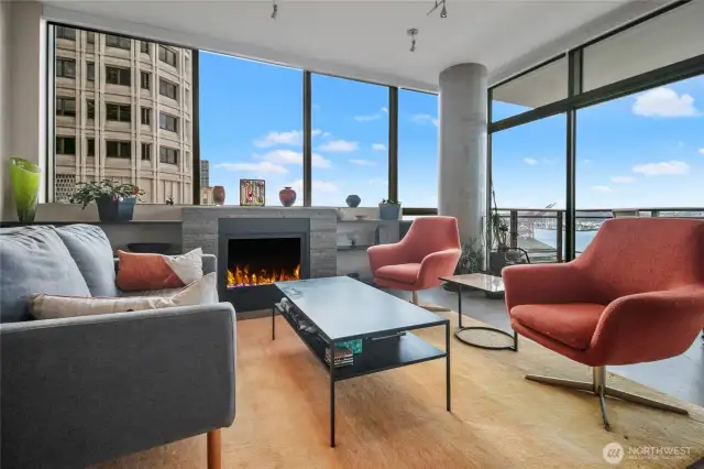 Cozy glass fireplace is flanked by bookshelves to display your treasures. Access to the deck is immediately behind the chairs.