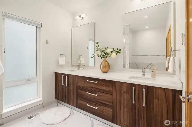 A view of the primary bathroom. It's well-appointed with a large dual vanity and heated floors.
