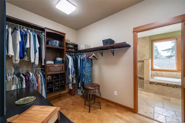 Primary Suite Walk in closet with built in shelving, soft cork flooring, and convenient access to the laundry room