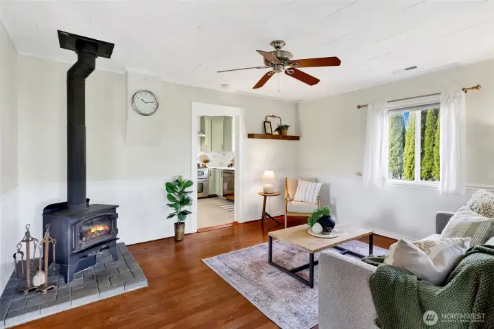 The living room features original wood floors and a cozy wood burning stove