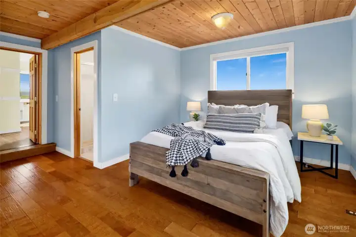 The primary bedroom is large and bright and features wood flooring, a cedar-lined closet, and an updated bathroom