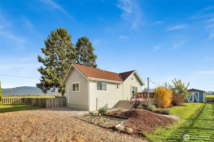 The large, flat yard is private and is set up for outdoor activities with a sandbox and garden space