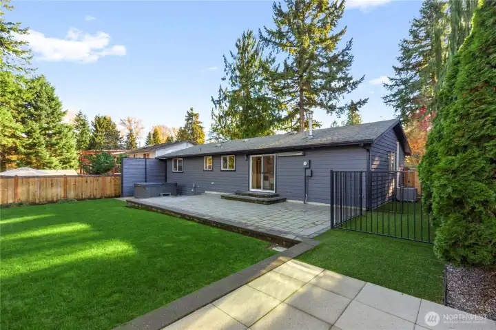 This listing features a spacious yard, a paved patio, and lush landscaping.