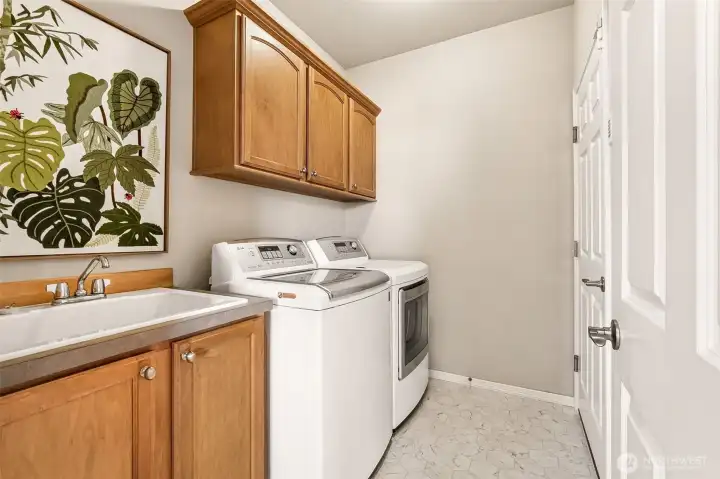 A spacious, organized laundry room with abundant storage makes everyday tasks easier. The built-in sink and cabinetry add convenience buyers truly appreciate. Easy access to and from the house via the garage. A spacious, organized laundry room with abundant storage makes everyday tasks easier. The built-in sink and cabinetry add convenience buyers truly appreciate. Easy access to and from the house via the garage.