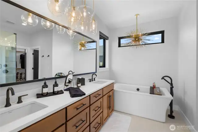 Primary bathroom featuring soaking tub and custom light fixtures throughout.