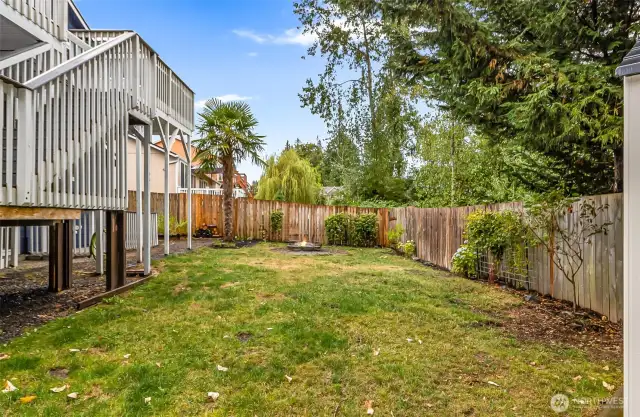 Fully fenced back yard with newer shed and fire pit.