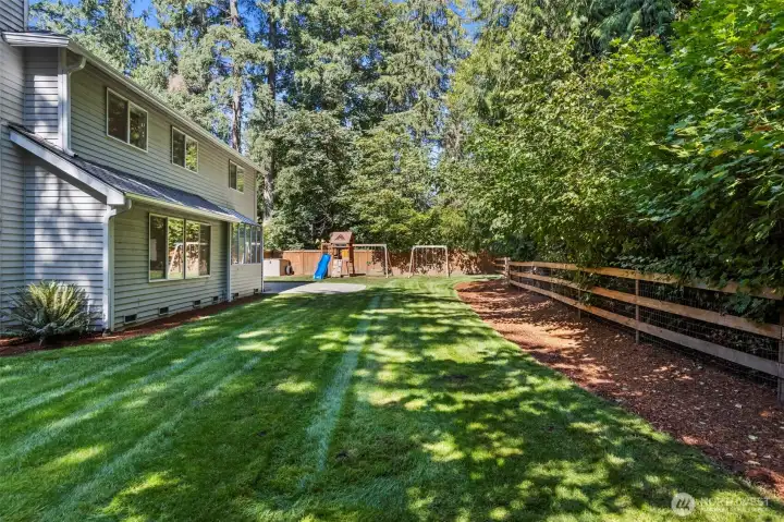 The fence along the grassline on the right is there only to set a boundary for the kids to play, but the back property line actually extends well up the hill to the top treeline