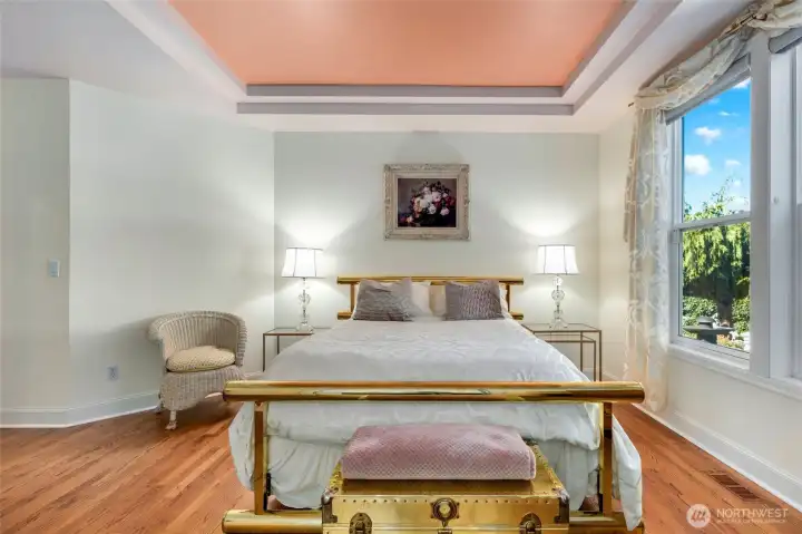 Primary bedroom with coffered ceiling and new flooring. Looks out onto the beautiful backyard.