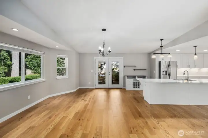 Open-concept main living area featuring hardwood floors, dining space, and a bright kitchen with quartz island and stainless appliances.