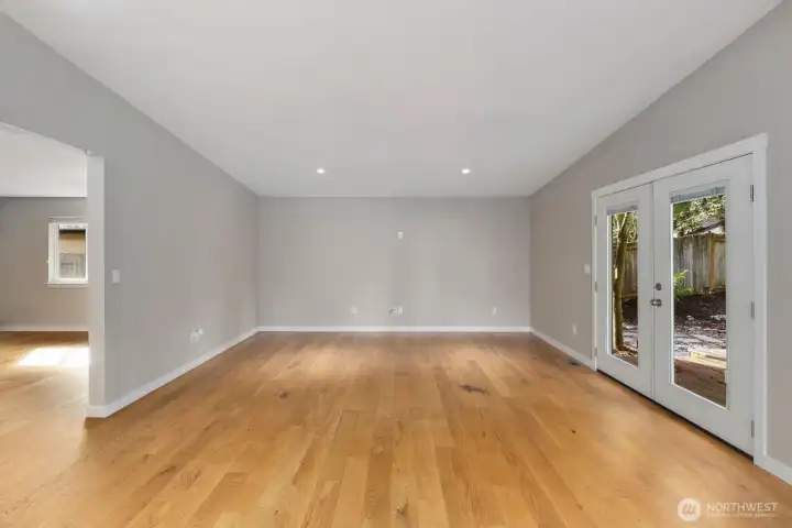 Large family room with recessed lighting, hardwood floors, and glass doors providing access to the backyard patio.