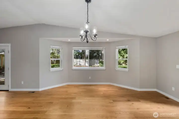 Dining area framed by multiple windows that bring in natural light and views of the surrounding yard.