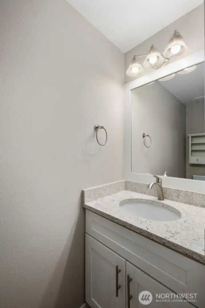Main-level powder bathroom with modern vanity, updated lighting fixture, and large mirror.