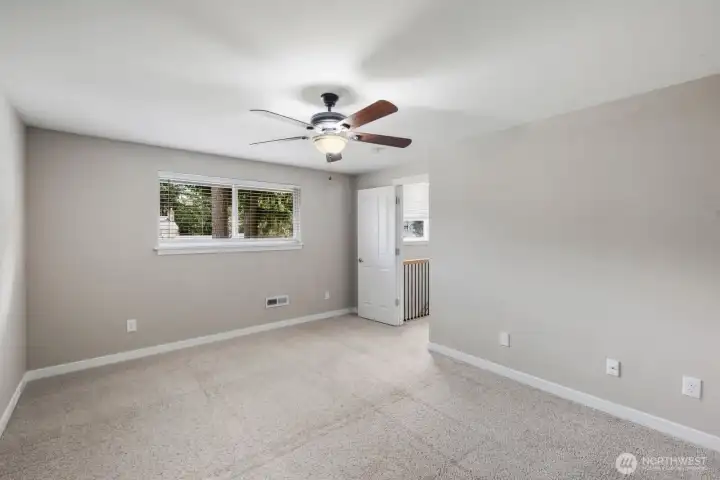 Light-filled bedroom with wide window, soft carpeting, and flexible space for furniture or home office setup.