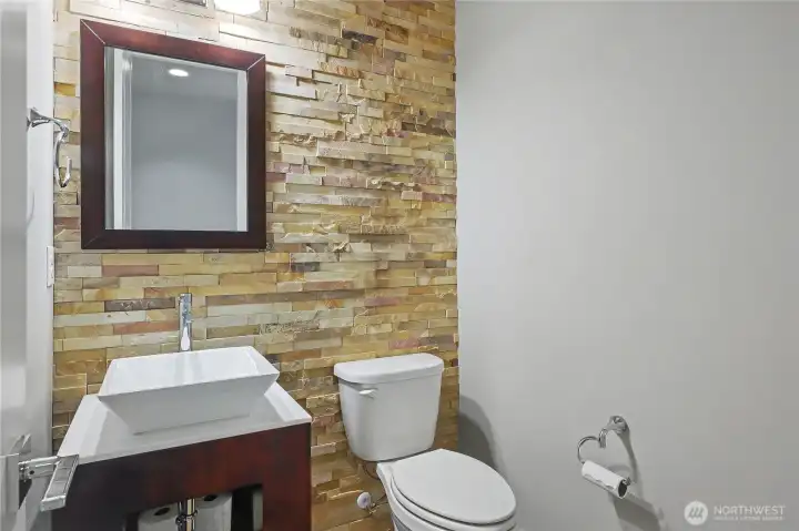 First floor powder room, so many quality aspects throughout this home! I love the floor-to-ceiling stone, the modern sink and vanity, AND the fact that this powder room is down the hall and not right off any living spaces!