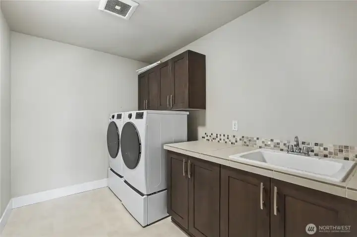 Upstairs laundry room - brilliant! After all, this is where all the clothes go off and on, no more hauling laundry baskets up and down! I LOVE the included, newer, high-capacity washer and dryer, the cabinetry & storage, and large utility sink! So many utility rooms are crammed and tiny - not this one.